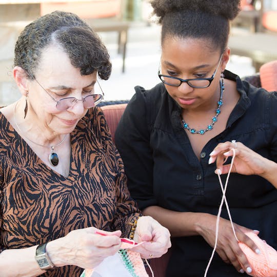 Elderly lady knitting being supported by her carer